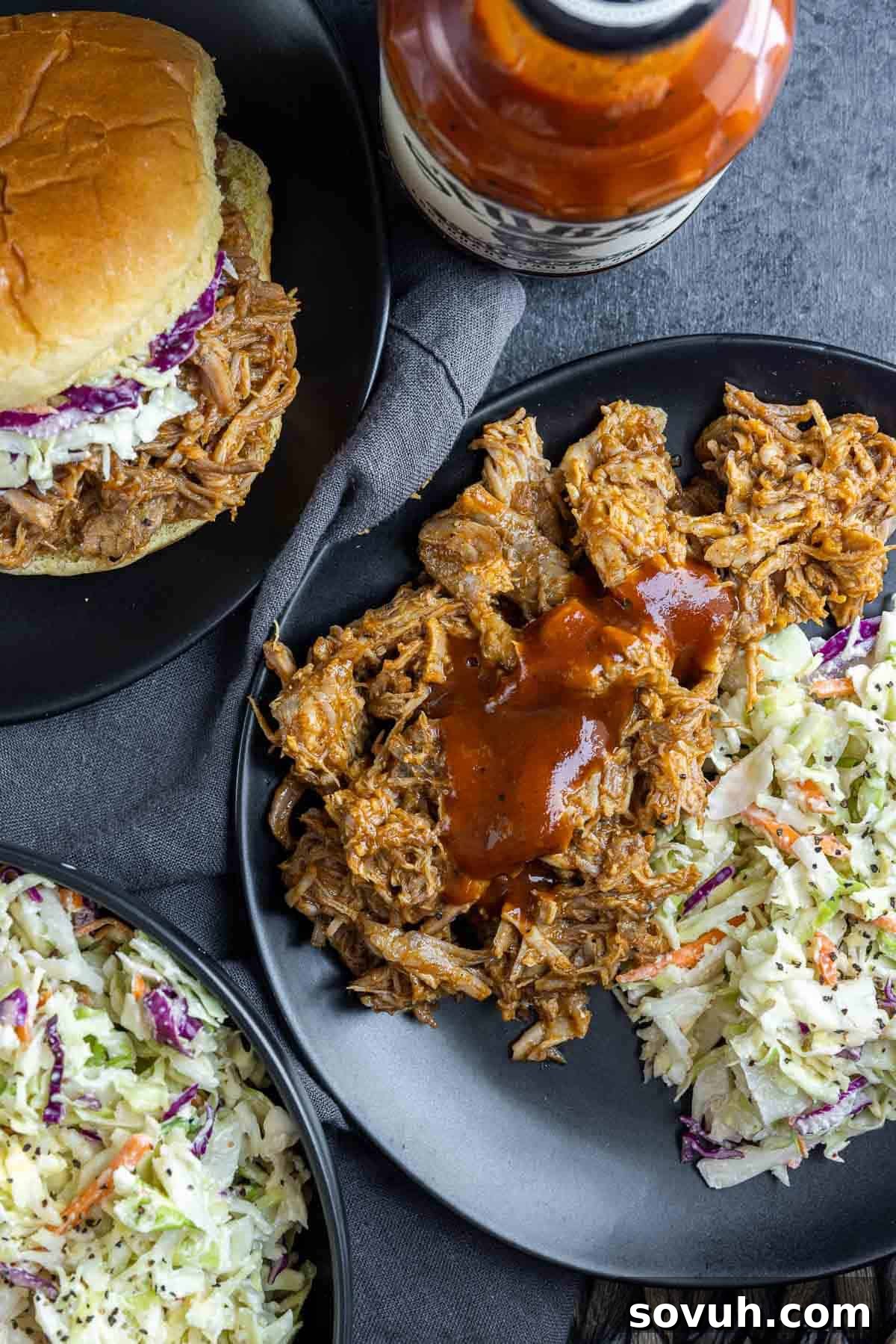 A plate featuring Slow Cooker BBQ Pulled Pork, served with coleslaw and a small slider bun, demonstrating a perfect meal.