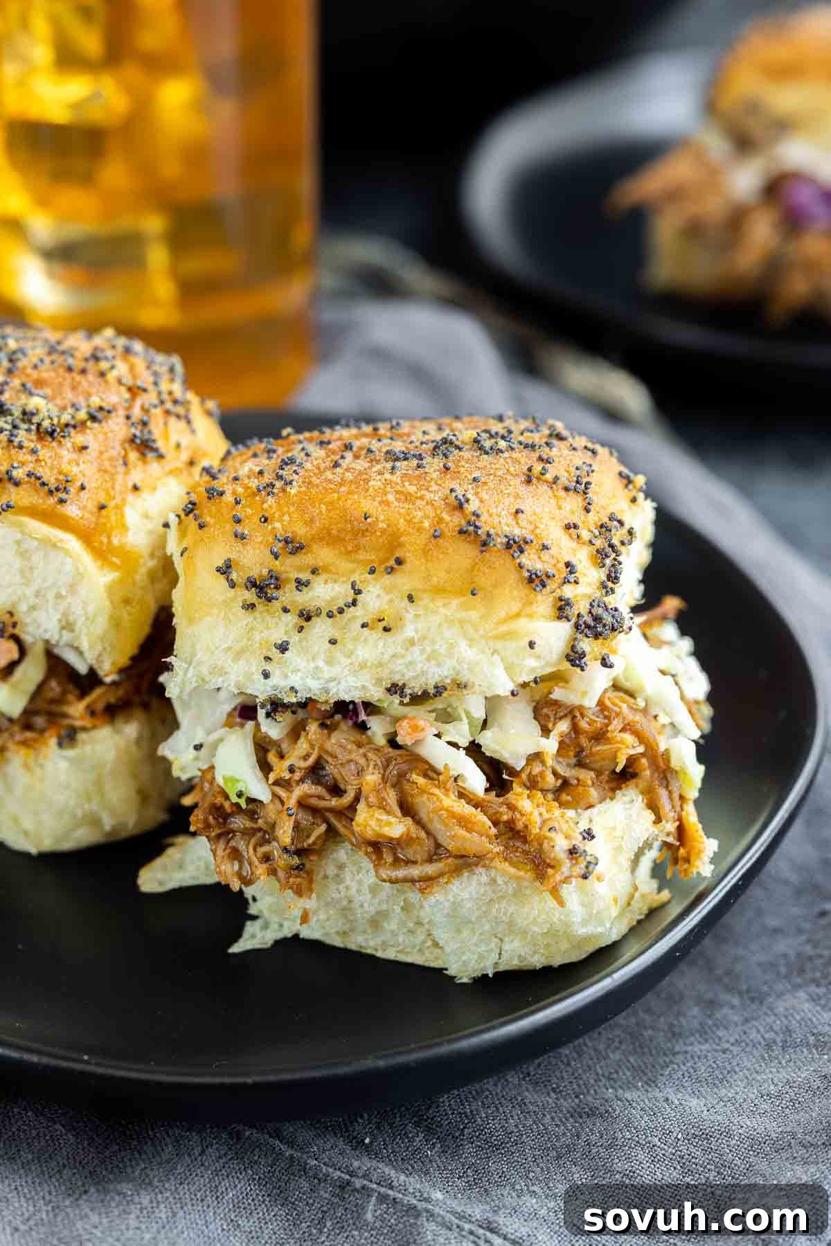 Close-up of BBQ Pulled Pork Sliders on a black plate, showcasing the vibrant colors and appealing texture