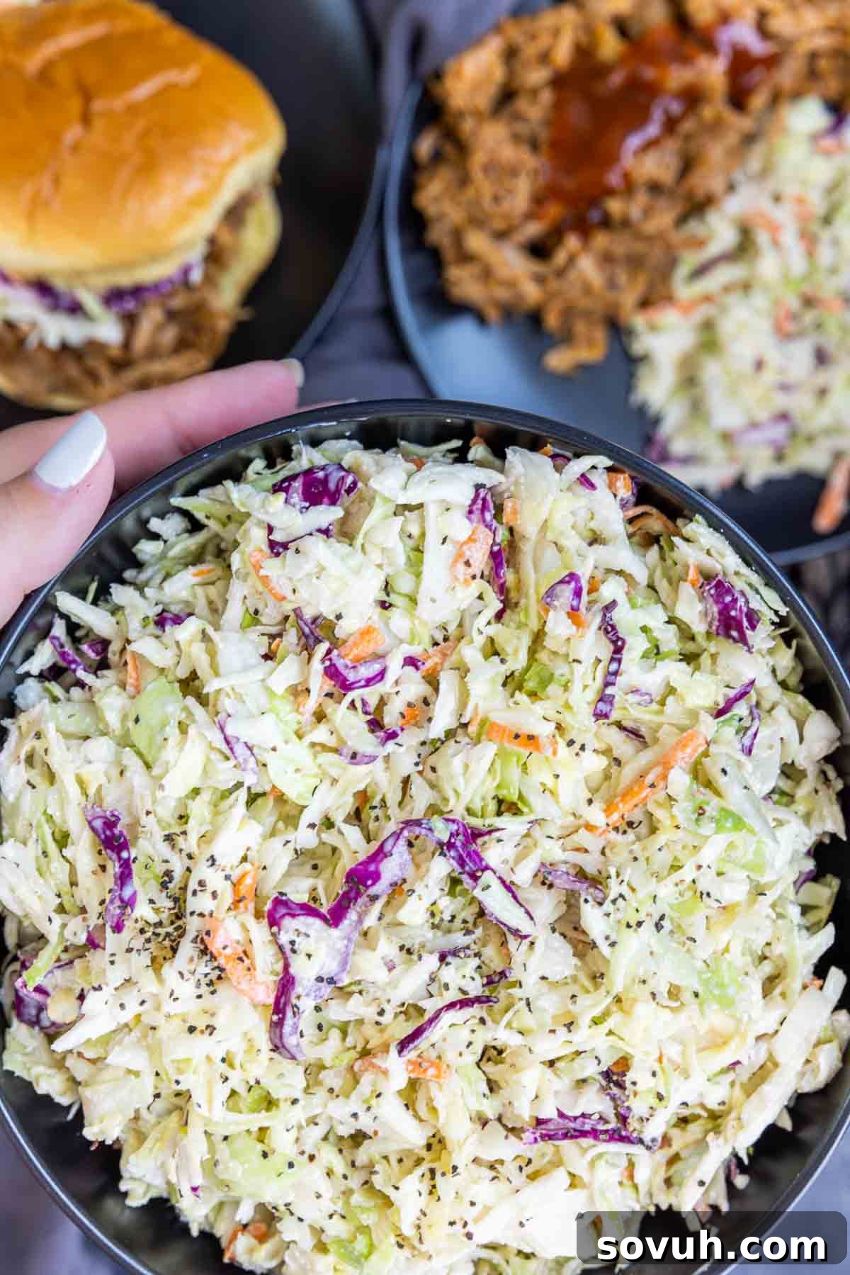Close-up of a black bowl of creamy Southern Coleslaw being held