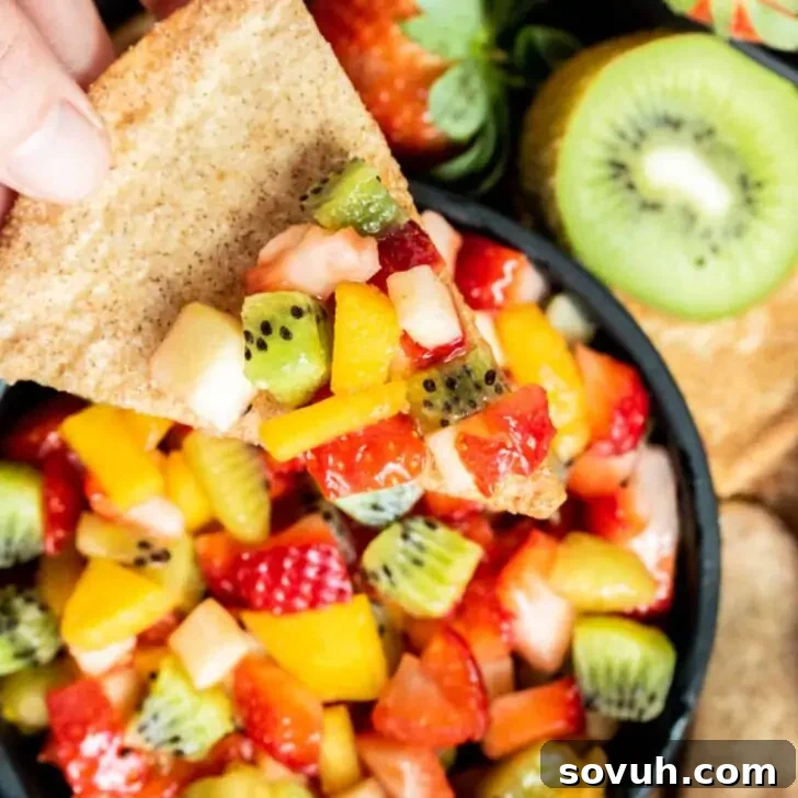 Scoop of sweet fruit salsa served on a crispy baked cinnamon chip
