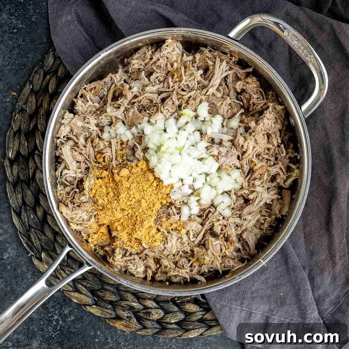 Seasoned pulled pork and diced onions cooking in a skillet for the enchilada casserole filling.