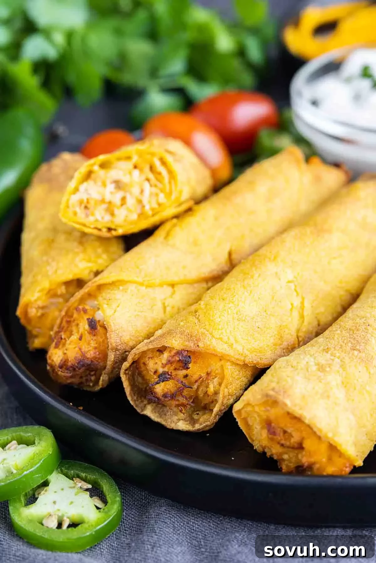 Air Fryer Taquitos on a black plate with jalapeno slices