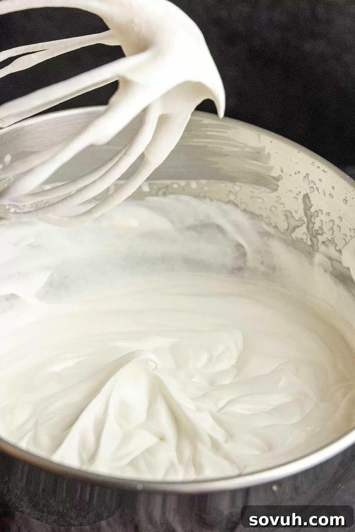 Stabilized whipped cream forming soft peaks in a mixing bowl, ready for further whipping or use.