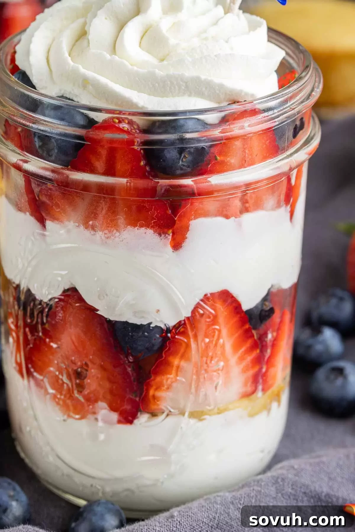 Close-up of a 4th of July cupcake in a jar, showing the distinct layers of cake, whipped cream, and fresh fruit.