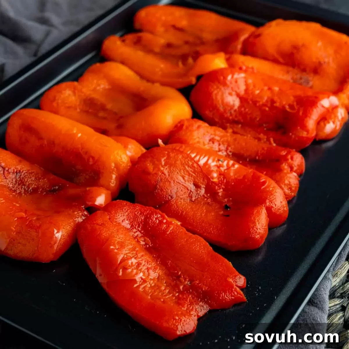 Red bell pepper halves meticulously arranged on a nonstick sheet pan, ready for roasting to achieve a delightful char and soften the texture