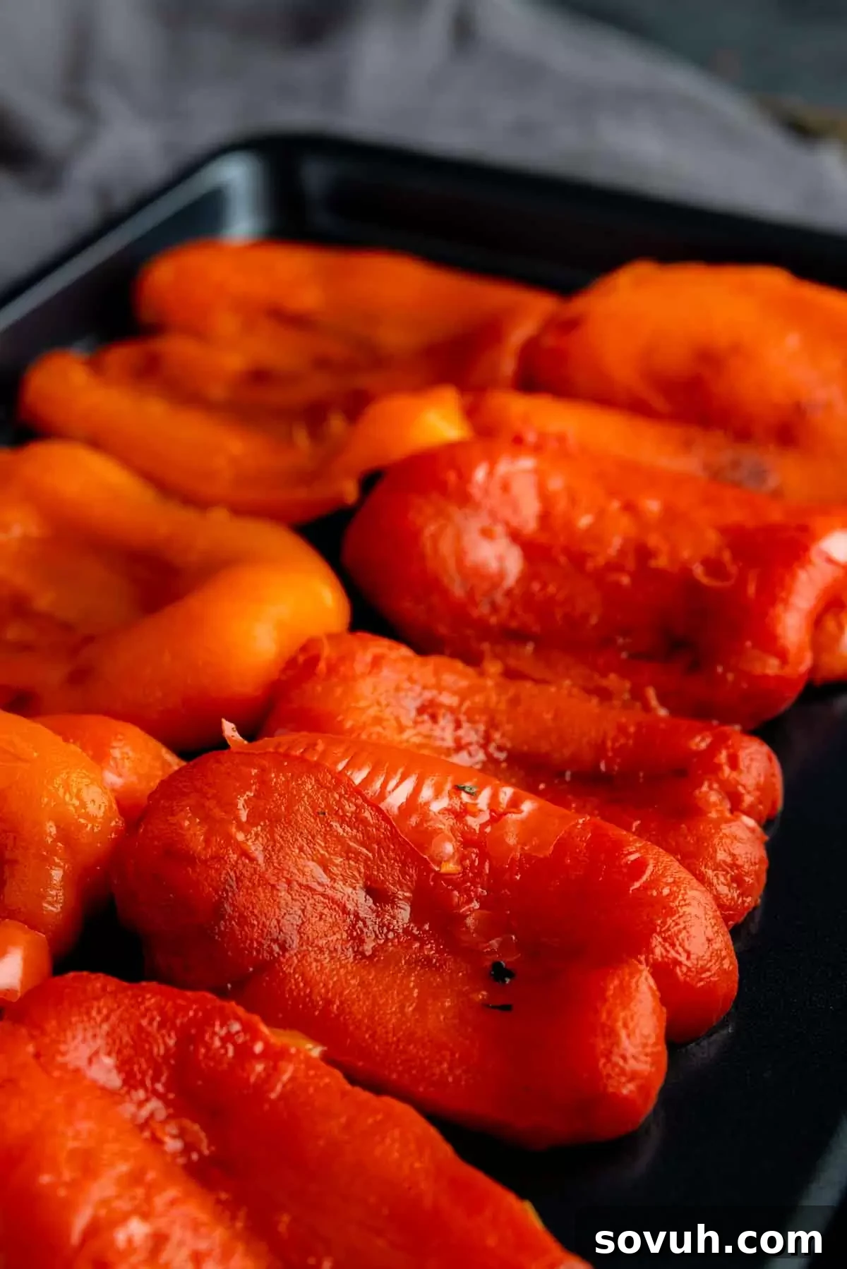 Assortment of roasted red bell pepper strips, beautifully peeled and glistening, arranged on a baking sheet, ready for storage or immediate use