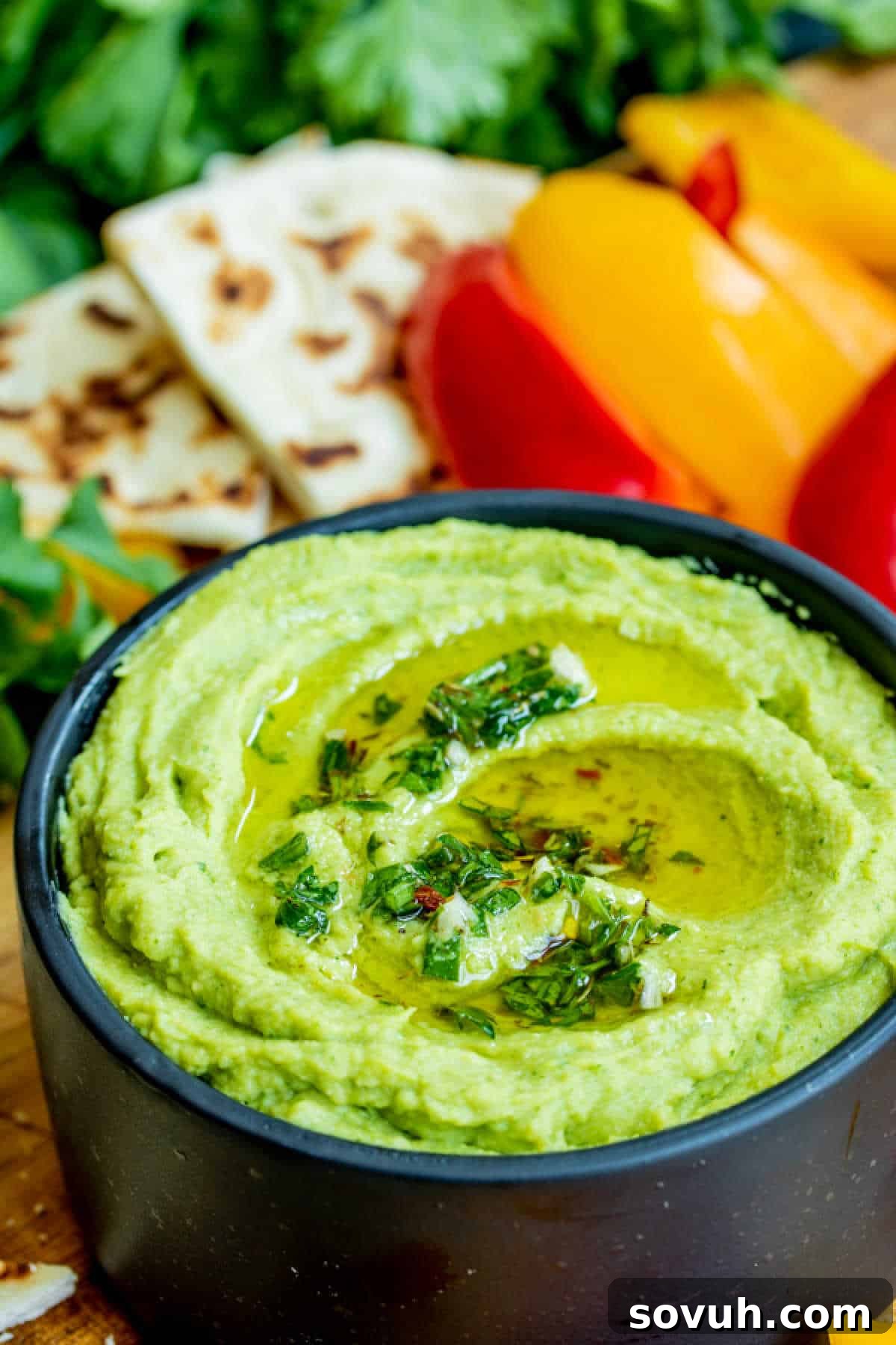Creamy Avocado Hummus served in an elegant black bowl, garnished with a sprig of cilantro.