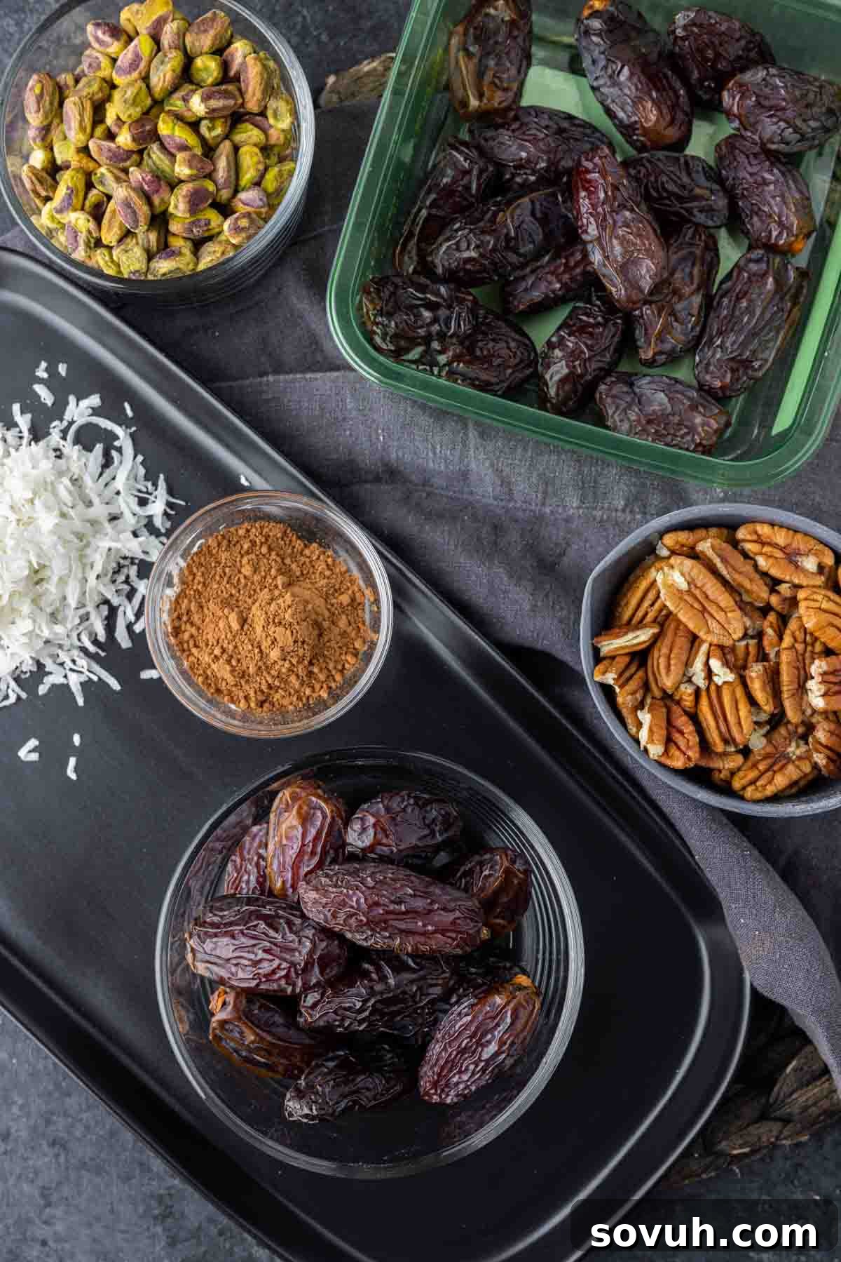 Bliss Balls 3 A simple yet inviting flat lay of the essential ingredients for date balls: plump whole dates, crunchy pecans, and rich cocoa powder, poised for preparation.