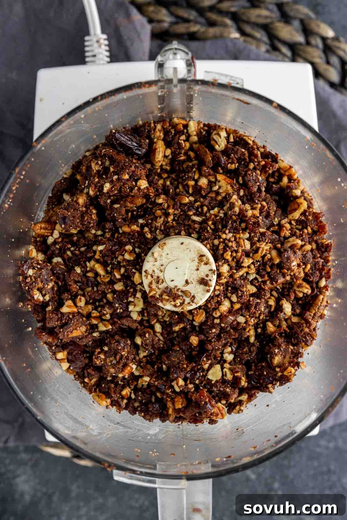 Bliss Balls 5 The perfectly blended, thick, and uniform mixture for date balls ready inside a food processor, showing its ideal consistency before rolling.