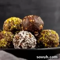 Delicious date balls rolled in coconut, arranged neatly on a black plate, showcasing their inviting texture and appearance.
