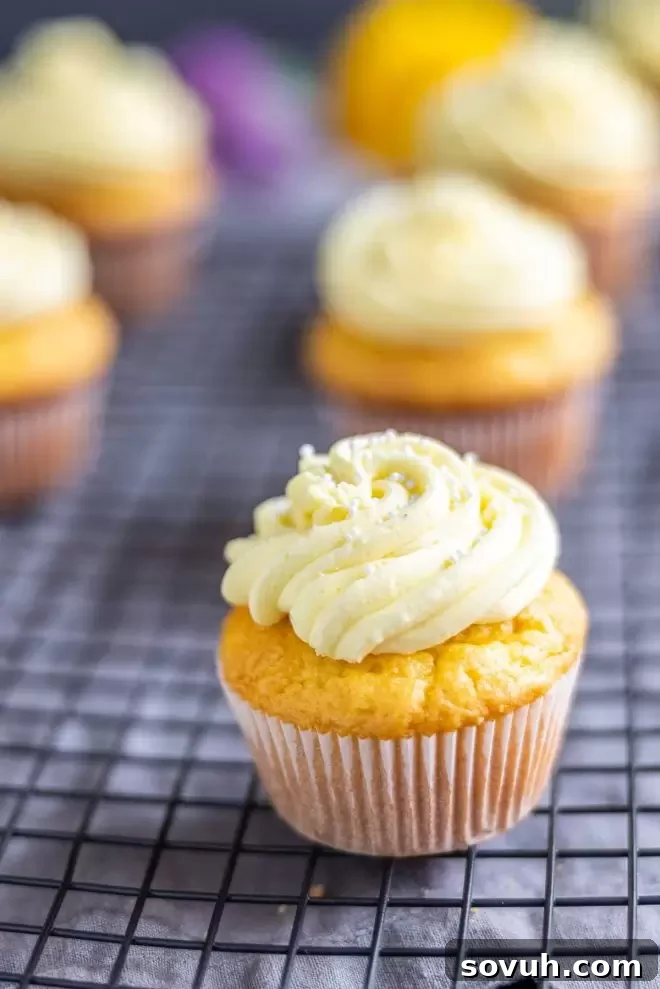 A beautifully frosted lemon cupcake adorned with white sprinkles on top of a yellow swirl of buttercream.