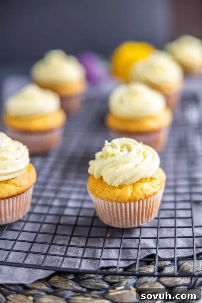 Several lemon cupcakes with yellow frosting on a cooling rack, ready to be enjoyed.