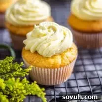 Close up of a single lemon cupcake with white sprinkles on top of yellow frosting.