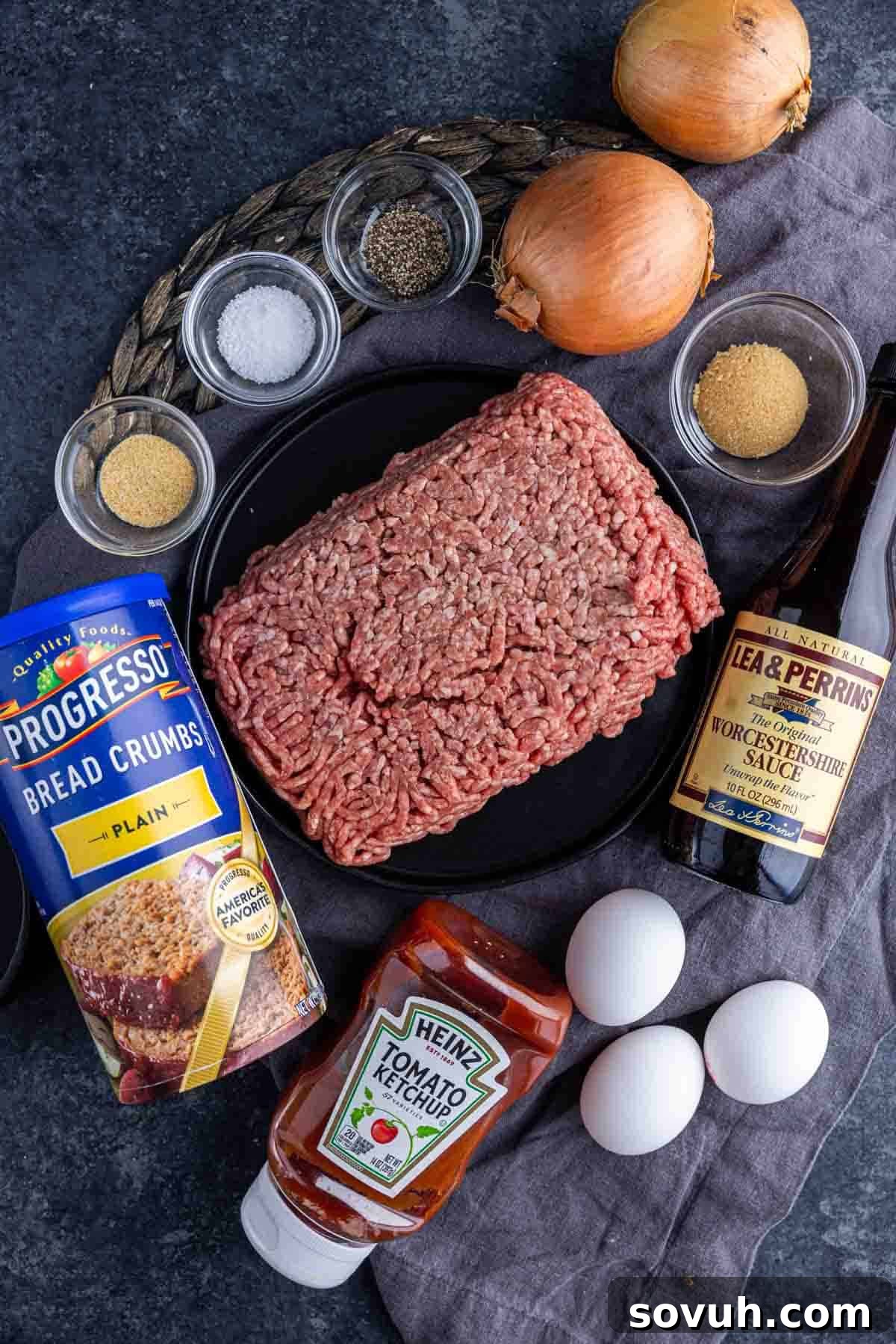 Fresh ingredients laid out for an easy meatloaf recipe, including ground beef, breadcrumbs, onion, and seasonings