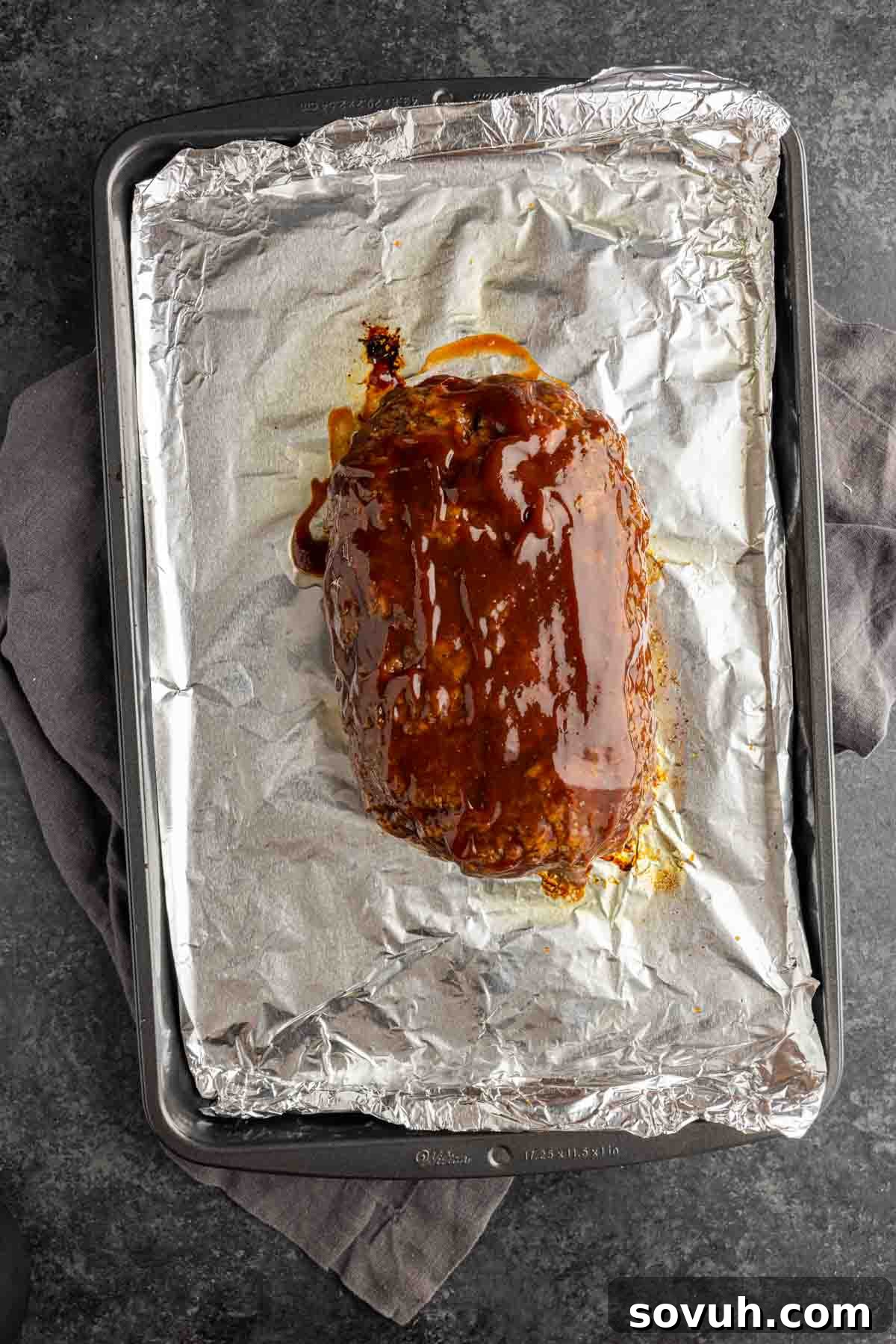 Partially baked meatloaf, glistening with a freshly applied glaze