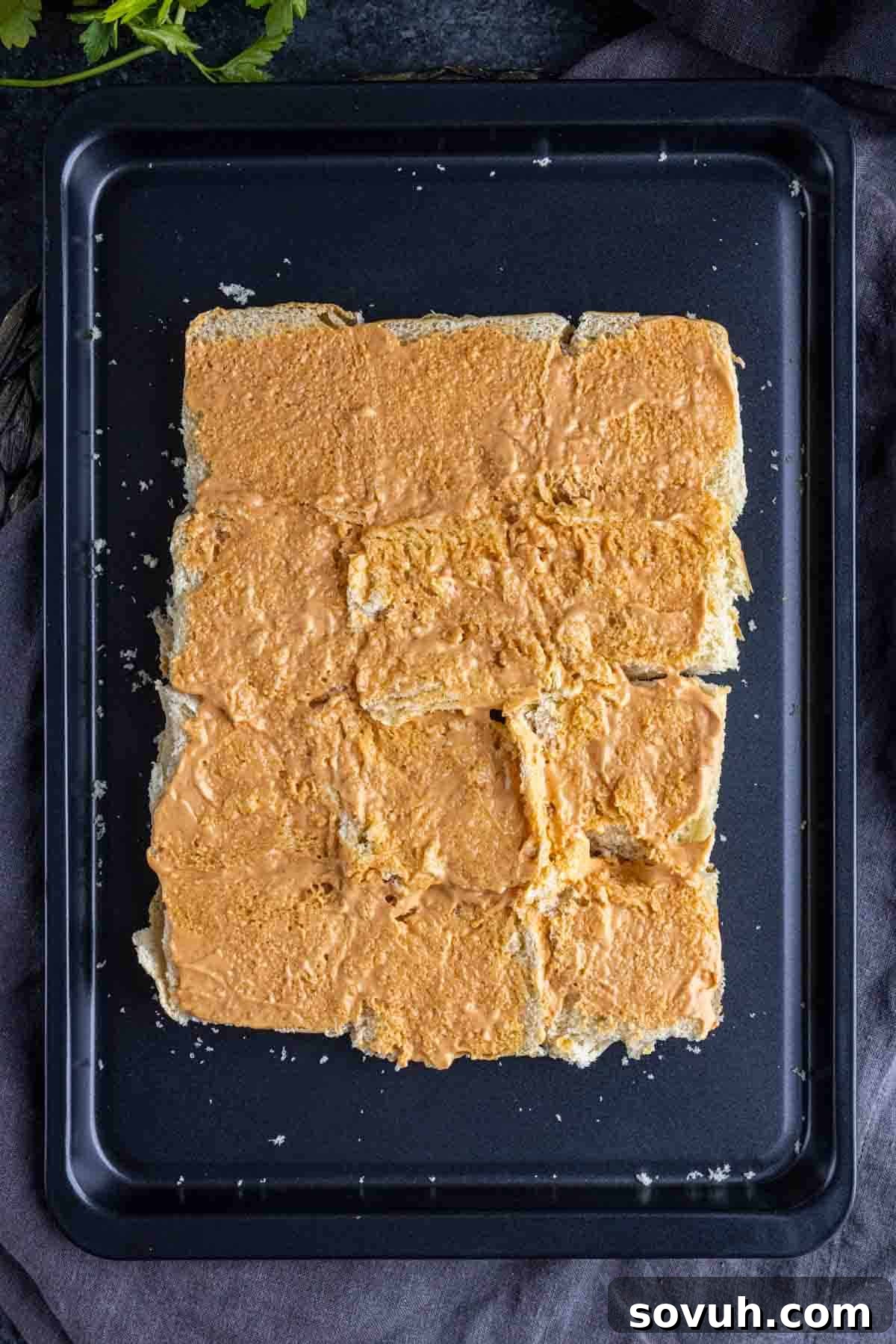 Applying chipotle mayo on the bottom buns of Turkey Sliders.