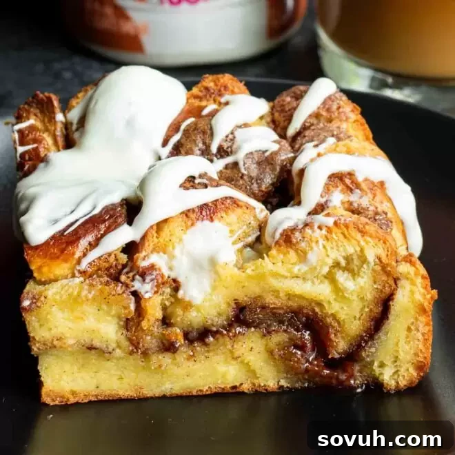 A mouth-watering piece of cinnamon roll casserole with a generous swirl of white icing on a plate.