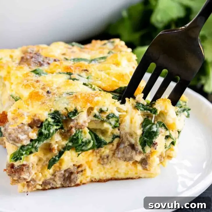 A delectable slice of Sausage and Spinach Quiche on a plate with a fork, highlighting its wholesome ingredients.