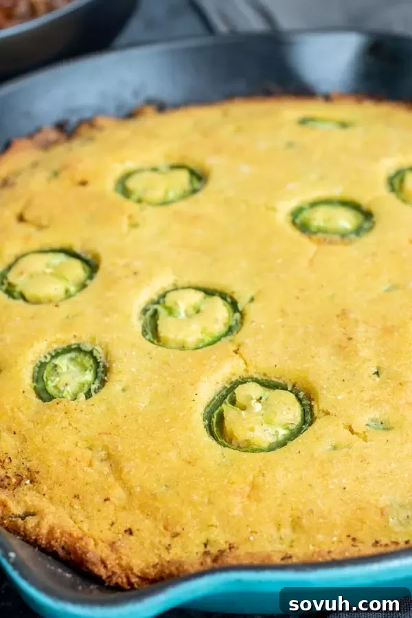 A close-up shot of a wedge of quick and easy skillet Jalapeno Cheddar Cornbread, showing its moist crumb and crispy edges.