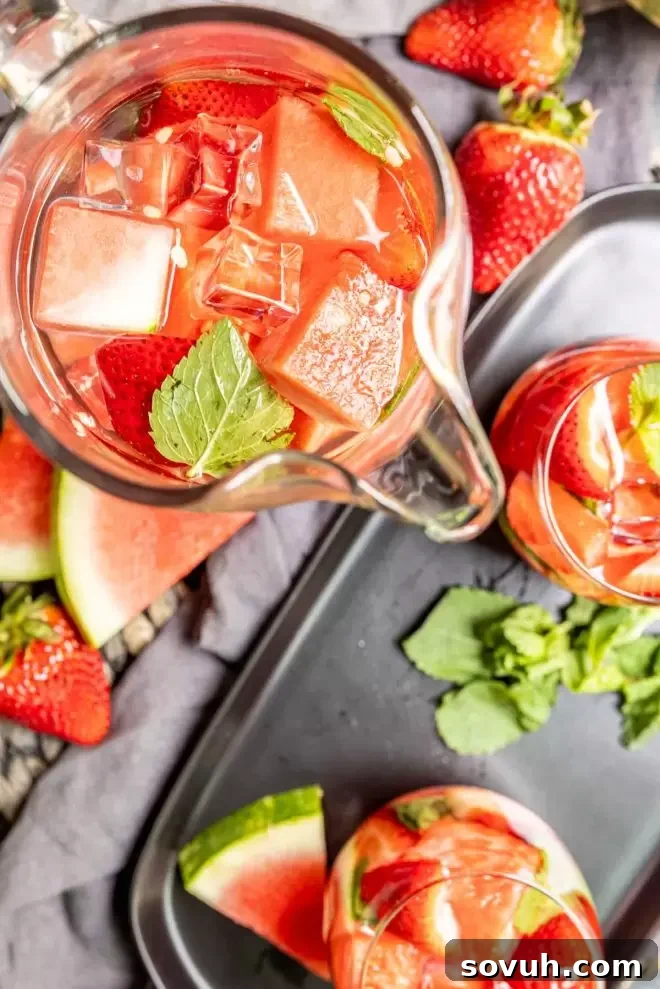 A pitcher of strawberry watermelon infused water with fruit and mint visible