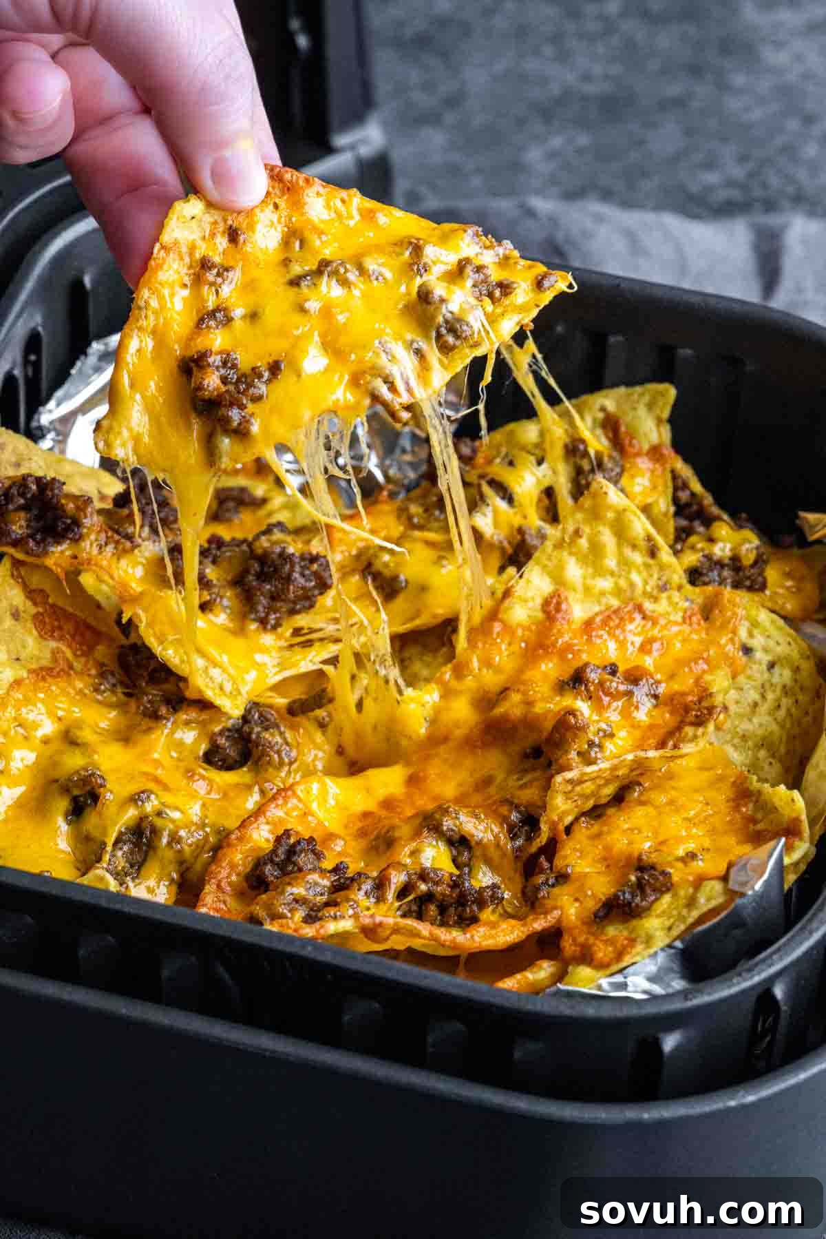 pulling Air Fryer Nachos out of the air fryer basket