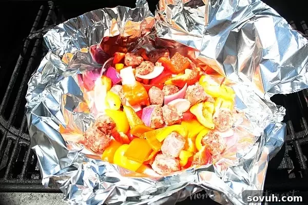A vibrant Italian Sausage and Pepper Foil Packet cooked on the grill, showcasing a medley of red and yellow bell peppers, onions, and sliced Italian sausage.