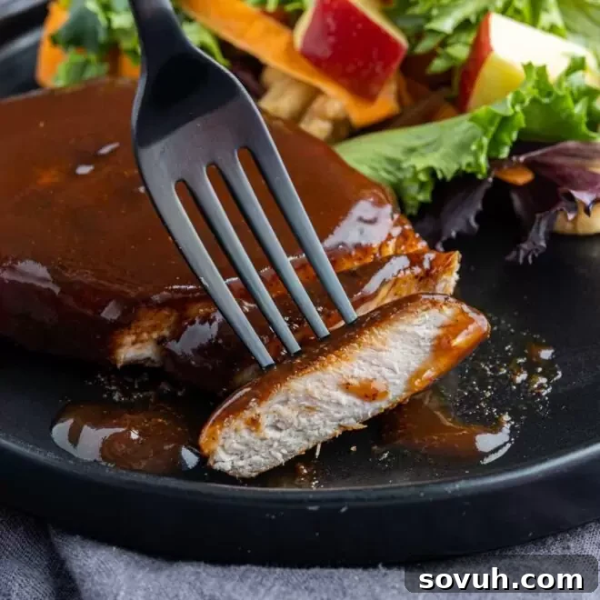 cut Air Fryer BBQ Pork Chops on a black plate, showcasing their juicy interior and sticky glaze.