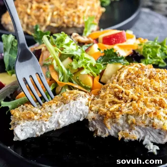 sliced Air Fryer Parmesan Crusted Pork Chops with black fork, revealing juicy meat.