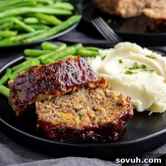 a black plate with Air Fryer Meatloaf, mashed potatoes and green beans, a complete comfort meal.