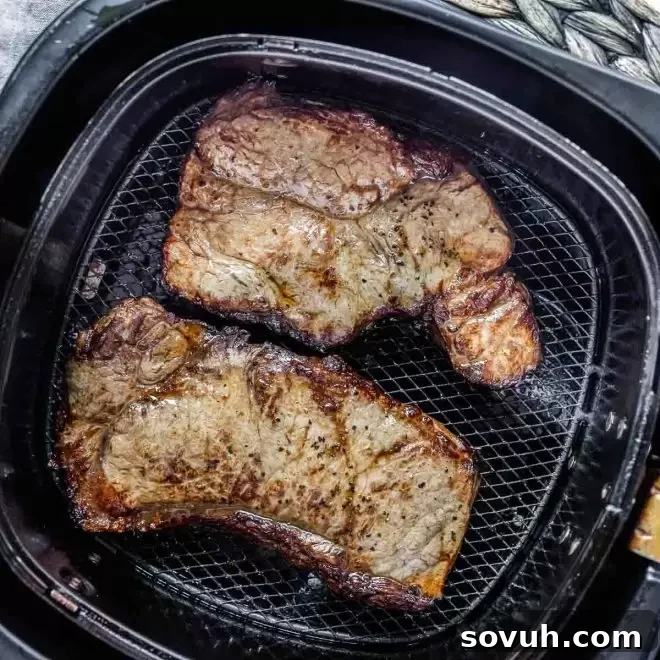 Air Fryer Steak in the air fryer, showing a perfectly seared cut.