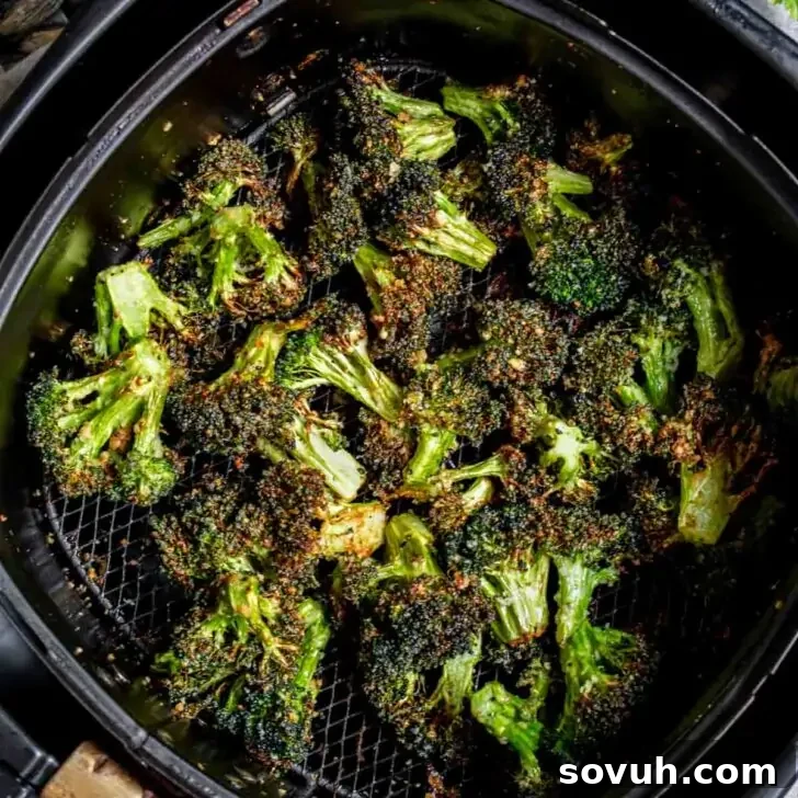 Air Fryer Broccoli with seasoning in an air fryer basket, showing perfectly roasted florets.