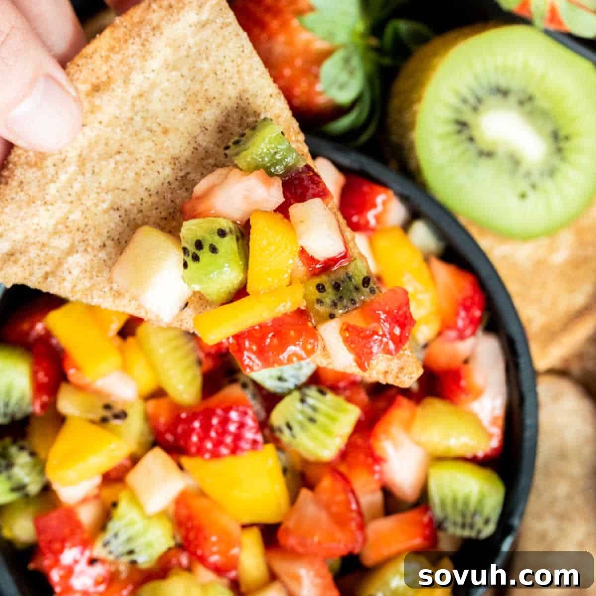 Scoop of colorful fruit salsa on a golden-brown baked cinnamon chip