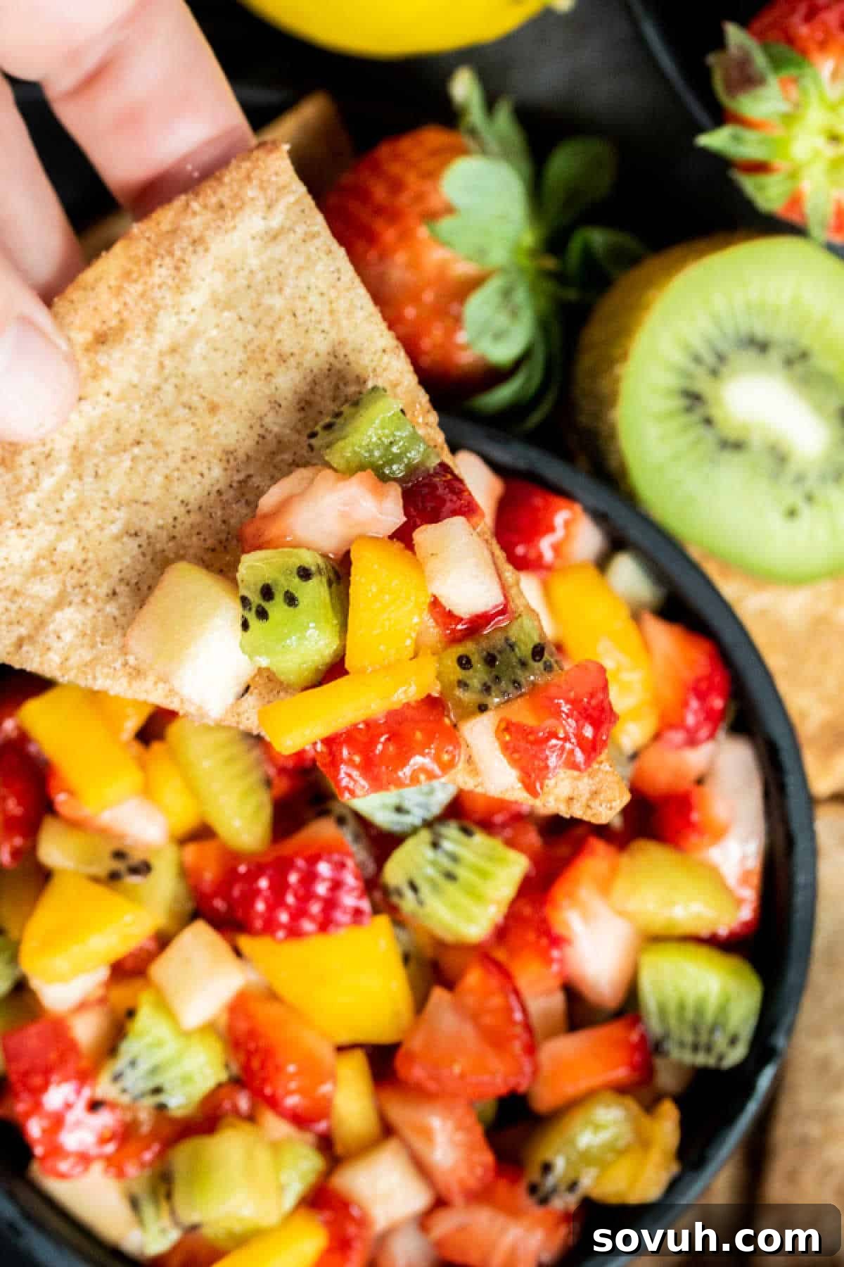 Scoop of fruit salsa on a baked cinnamon chip with a rustic background