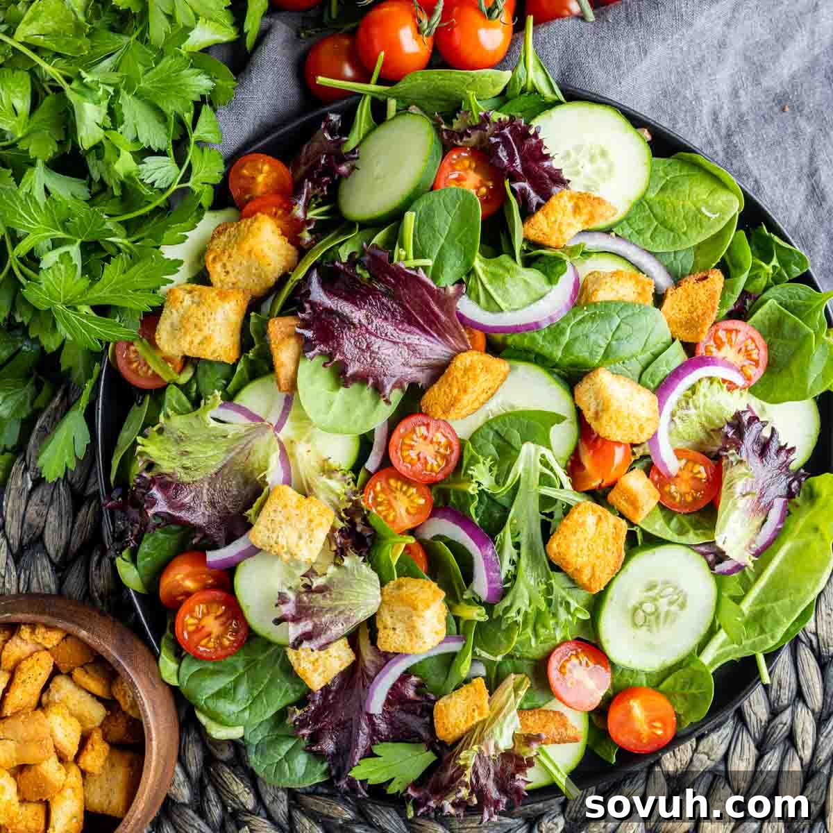 top down view of mixed green salad in black bowl, highlighting fresh ingredients