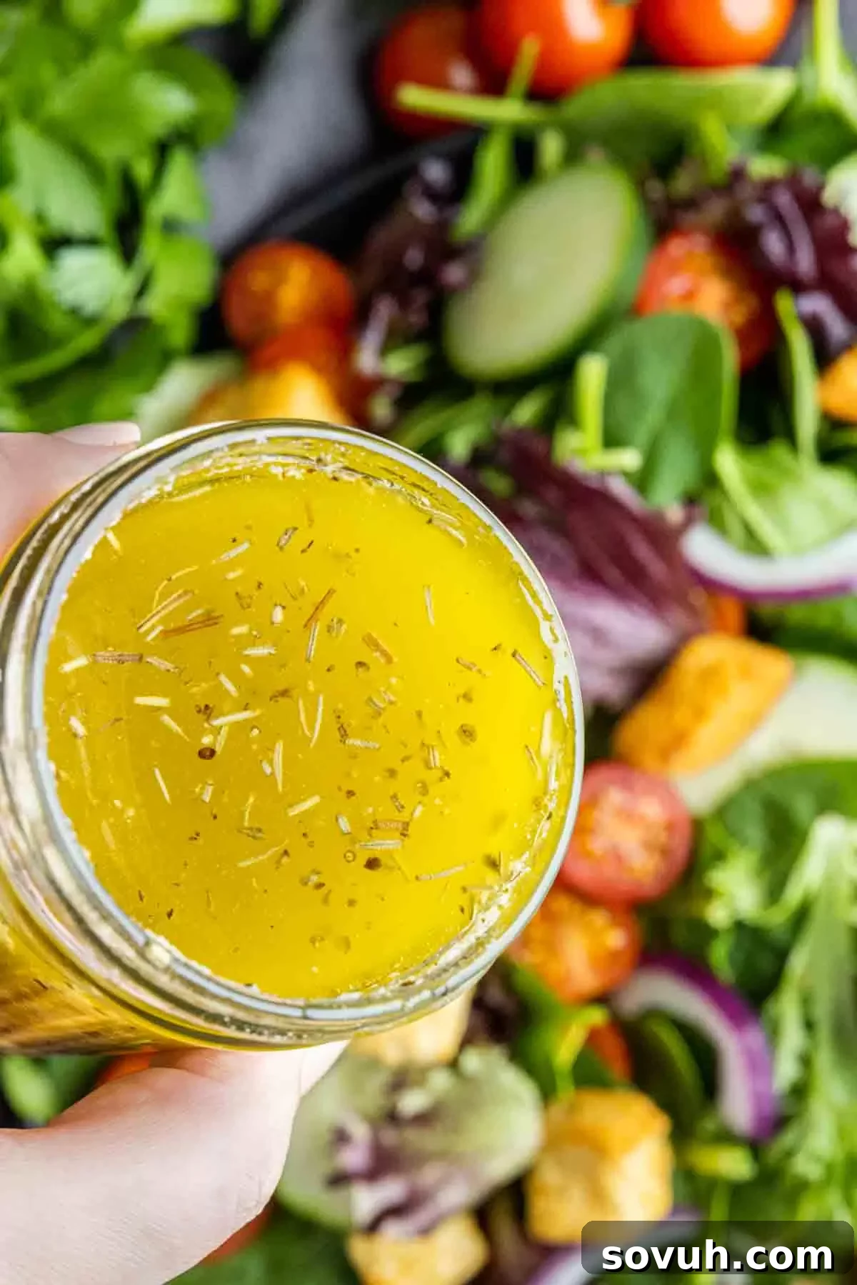 holding a a mason jar of Homemade Italian Dressing above a mesclun salad