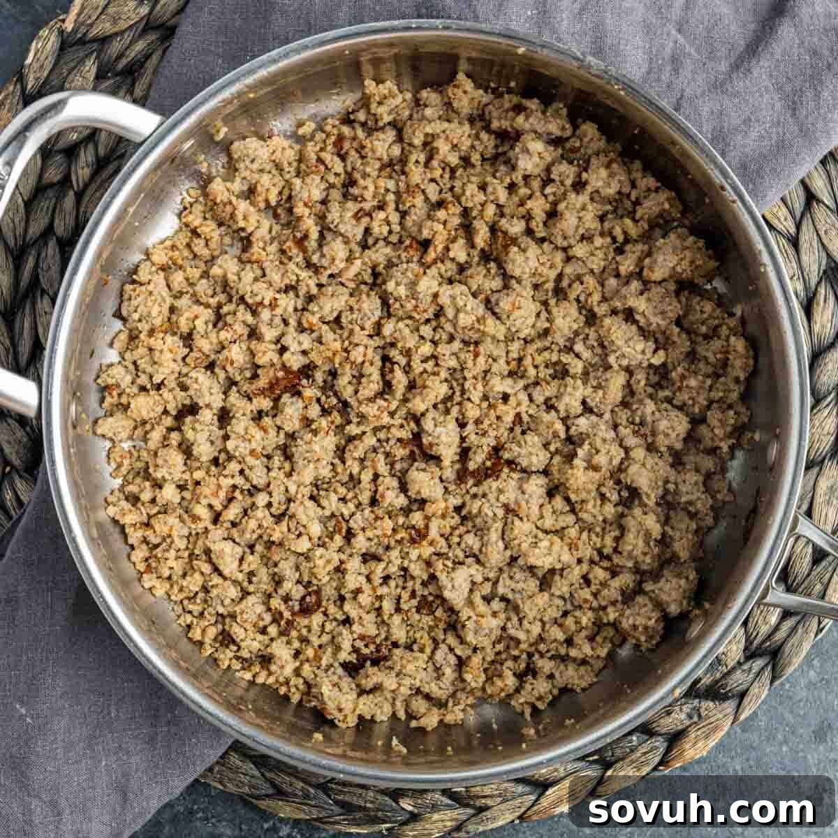 Ground sausage cooking in a skillet, browning evenly for the dip base.