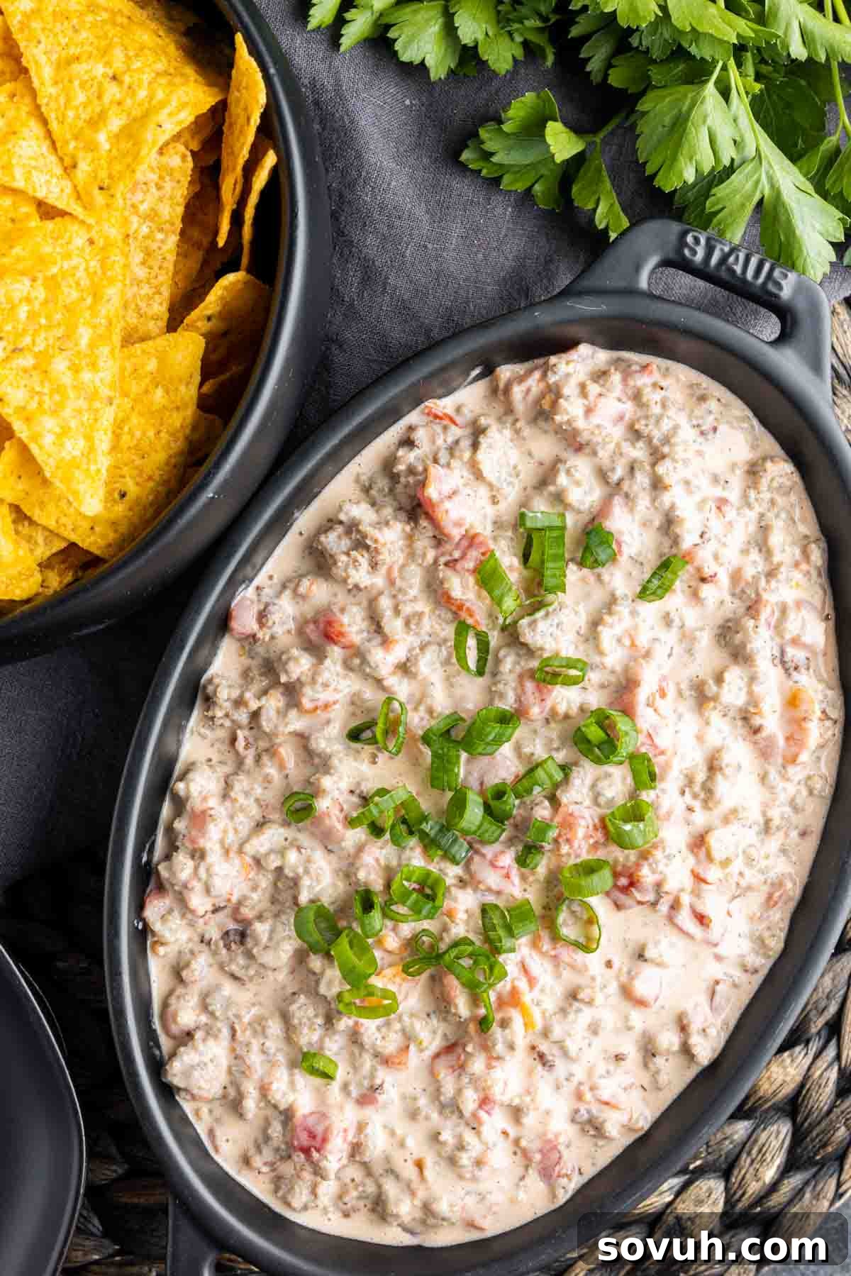 A bowl of creamy Sausage Cream Cheese Dip next to a bowl of tortilla chips, ready for serving.