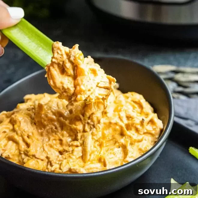 Dipping celery into a bowl of Instant Pot Buffalo Chicken Dip