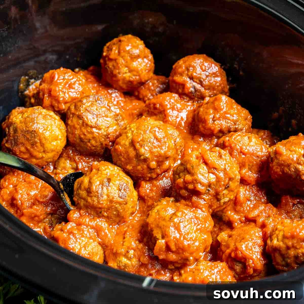 Frozen Meatballs in the Crock Pot with spoon in it