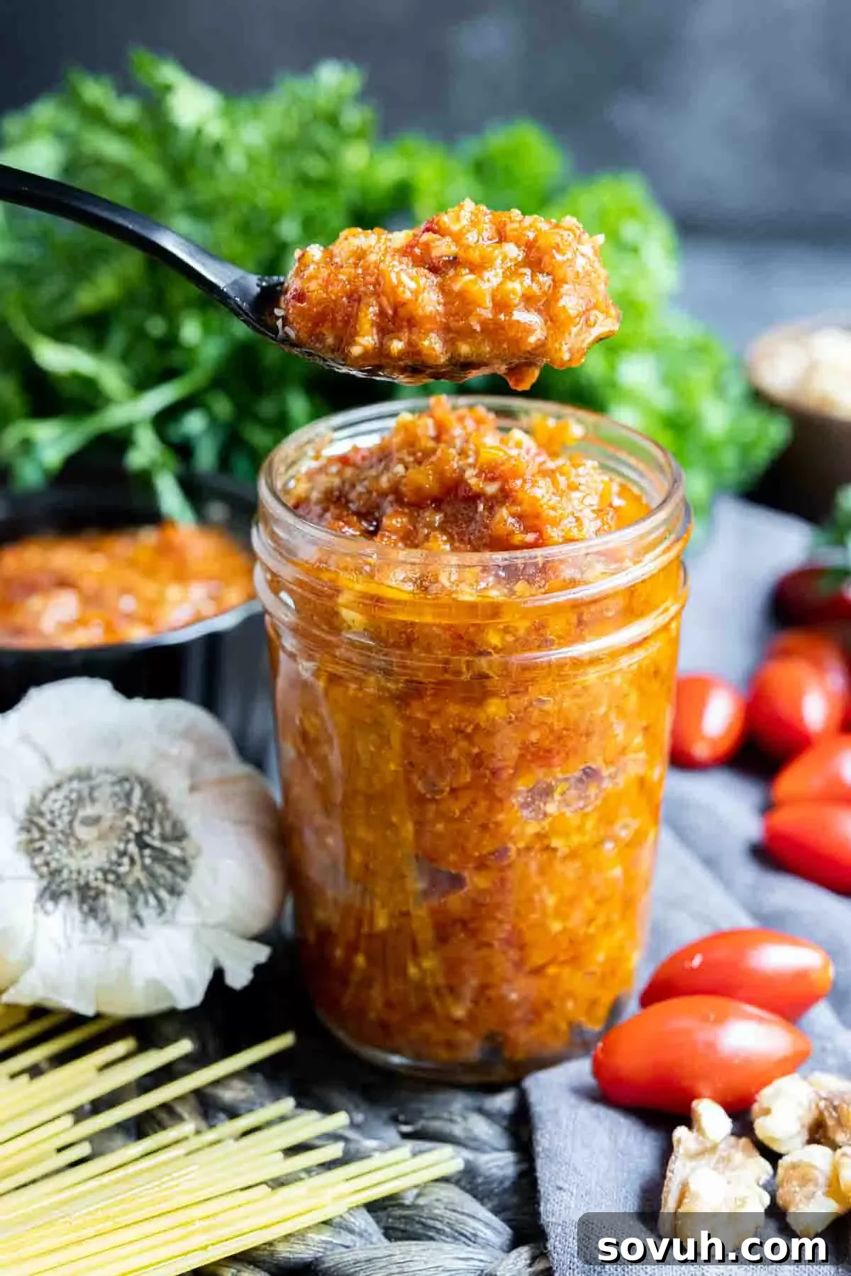 spoonful of Pesto Rosso over top a glass jar of Pesto Rosso