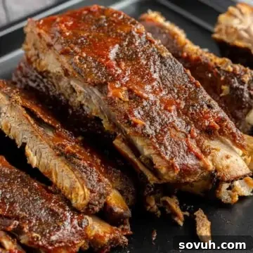 Succulent St. Louis-style ribs, slow-cooked to perfection, served on a black plate with tender meat falling off the bone.