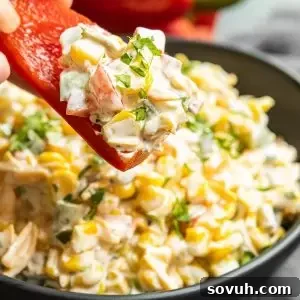 Red pepper slice with creamy Jalapeno Corn Dip on it, perfect for summer gatherings.