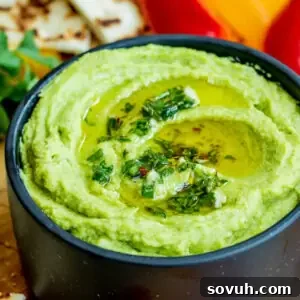A black bowl brimming with creamy, healthy Avocado Hummus, ready to be served.