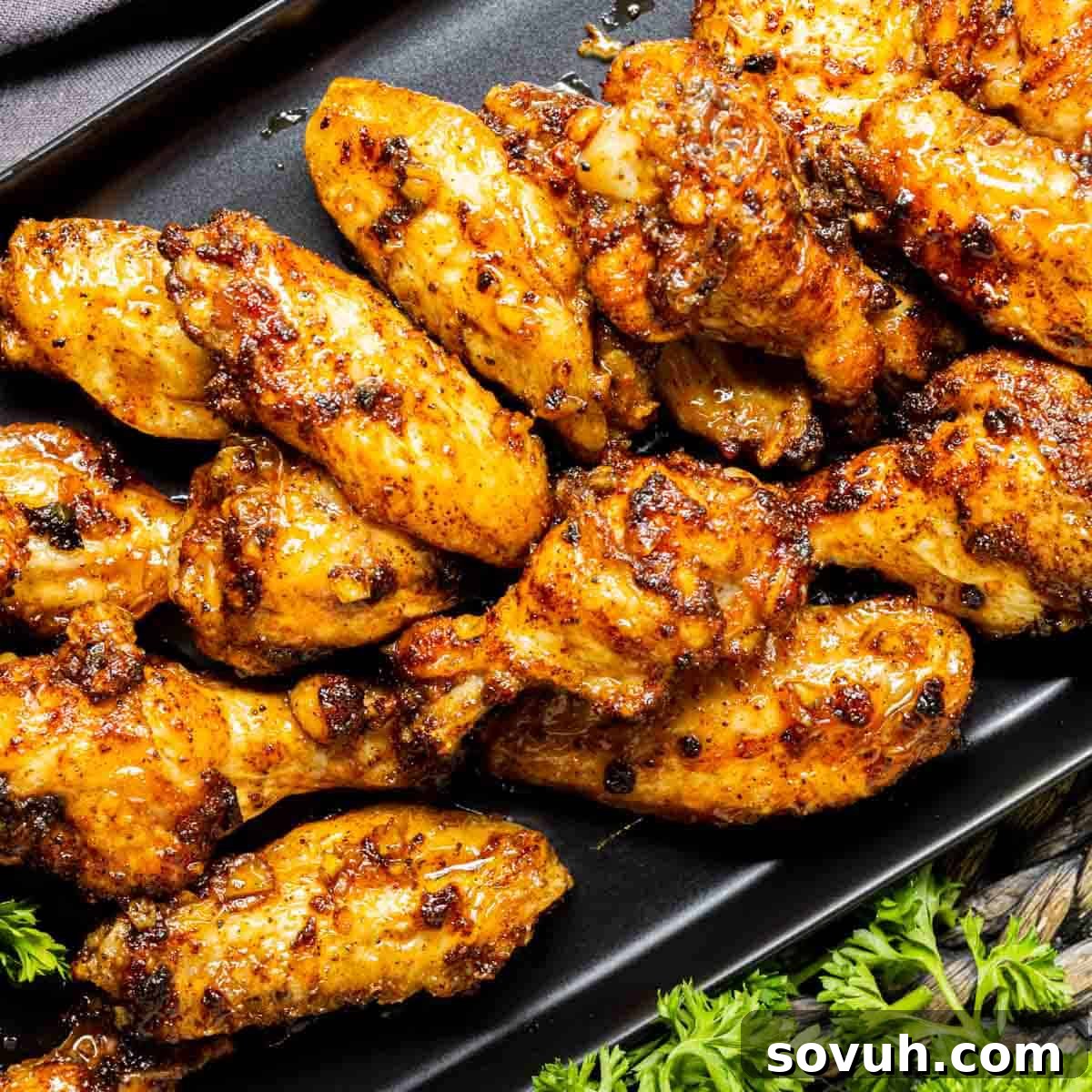 Crispy Air Fryer Honey Garlic Chicken Wings on a black plate with fresh parsley garnish.