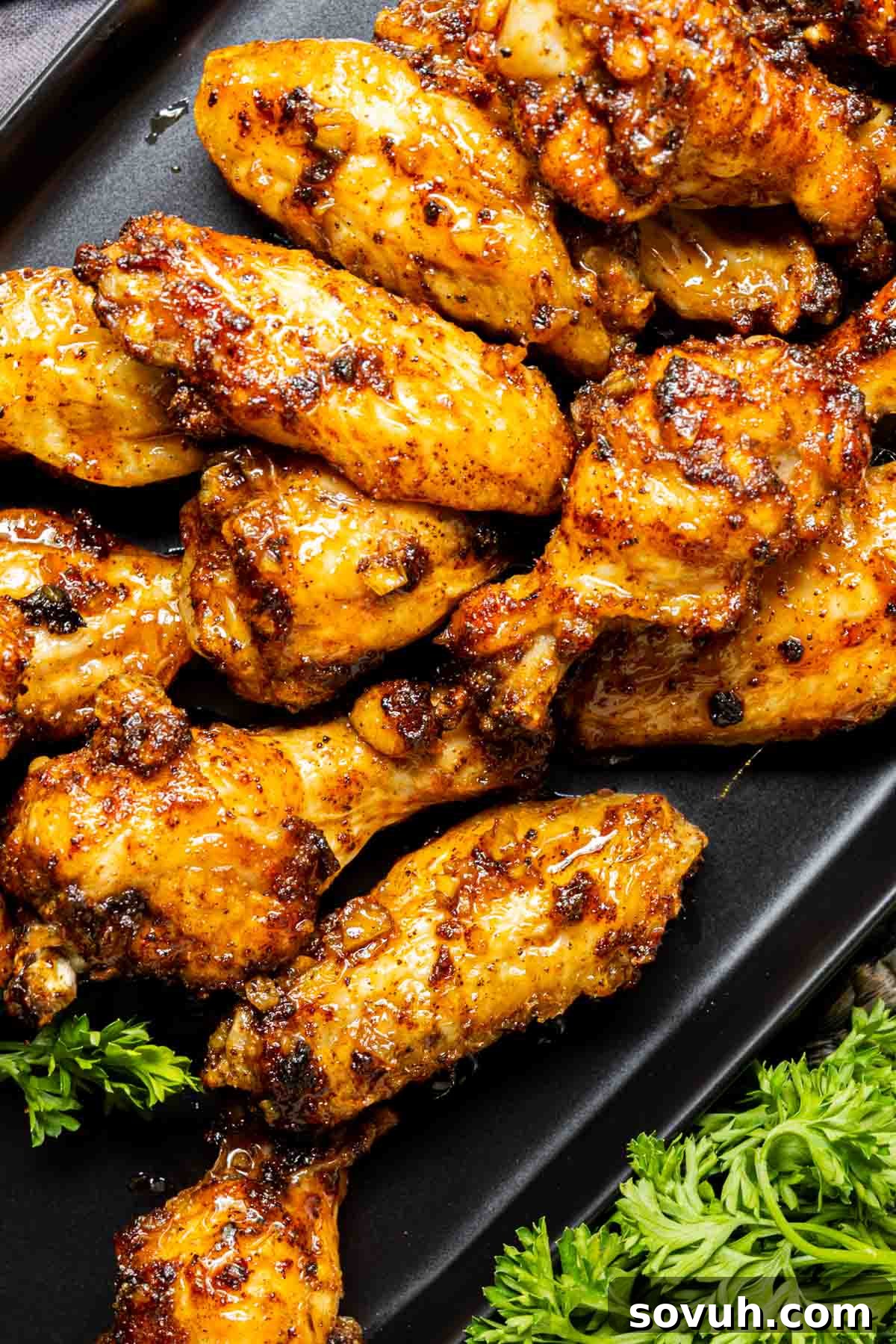 Honey Garlic Chicken Wings on a black plate with parsley.