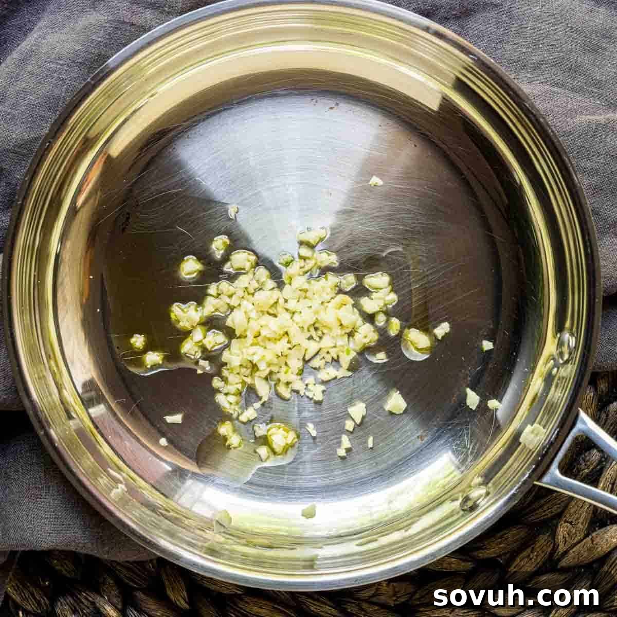A frying pan with minced garlic sizzling in olive oil, preparing for Honey Garlic Chicken Wings sauce.