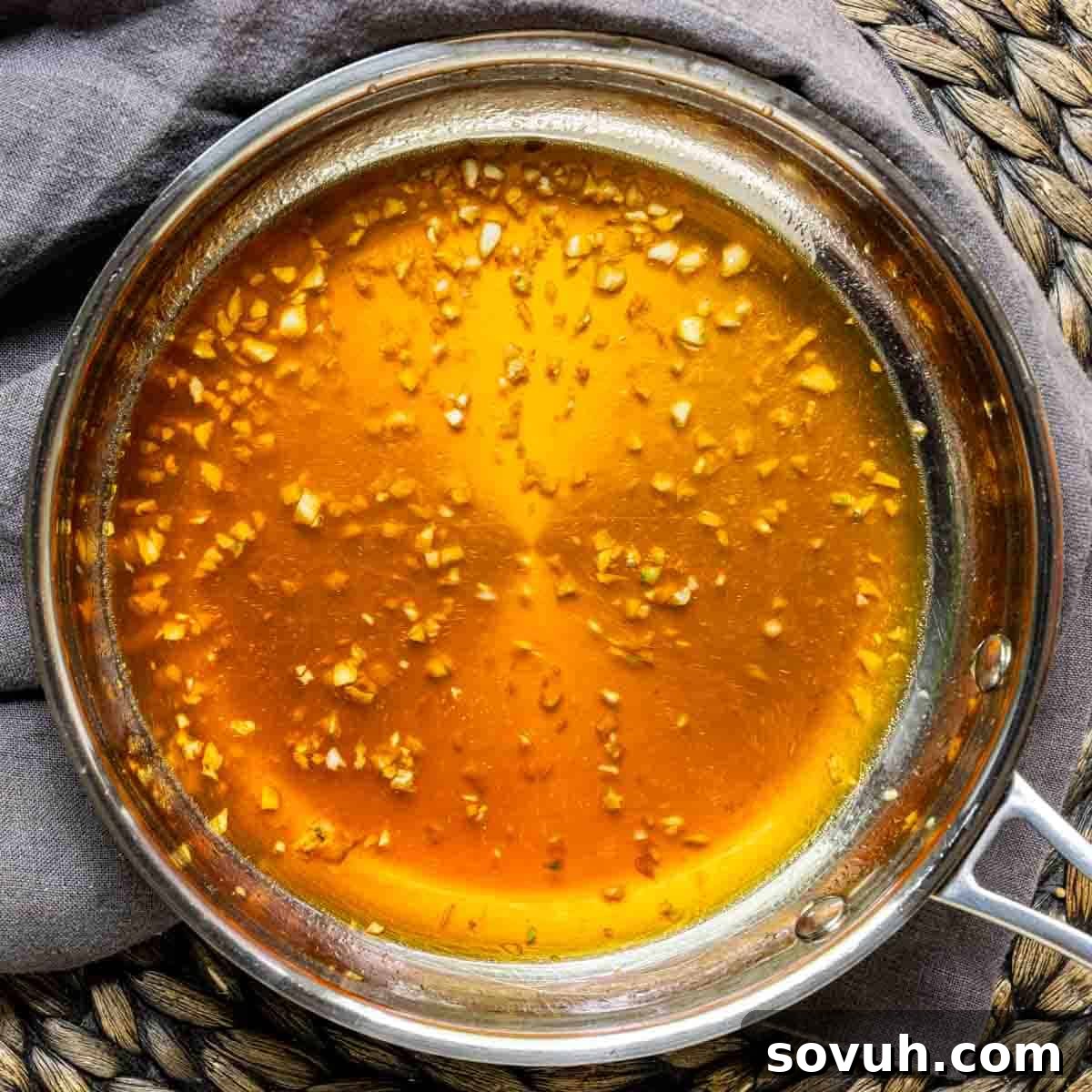 A pan with honey and garlic sauce simmering on a woven rattan surface, ready for Honey Garlic Chicken Wings.