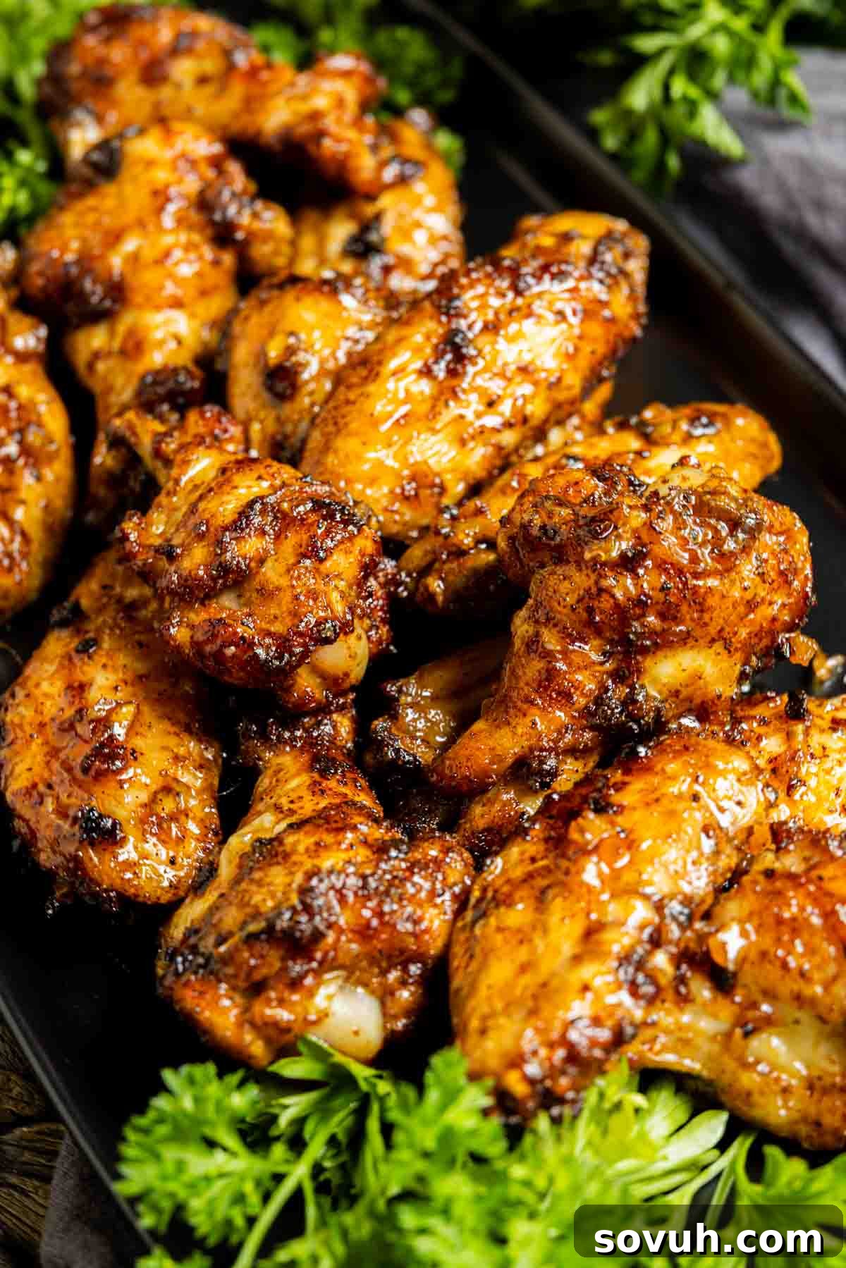 Honey Garlic Chicken Wings on a black plate with parsley garnish.
