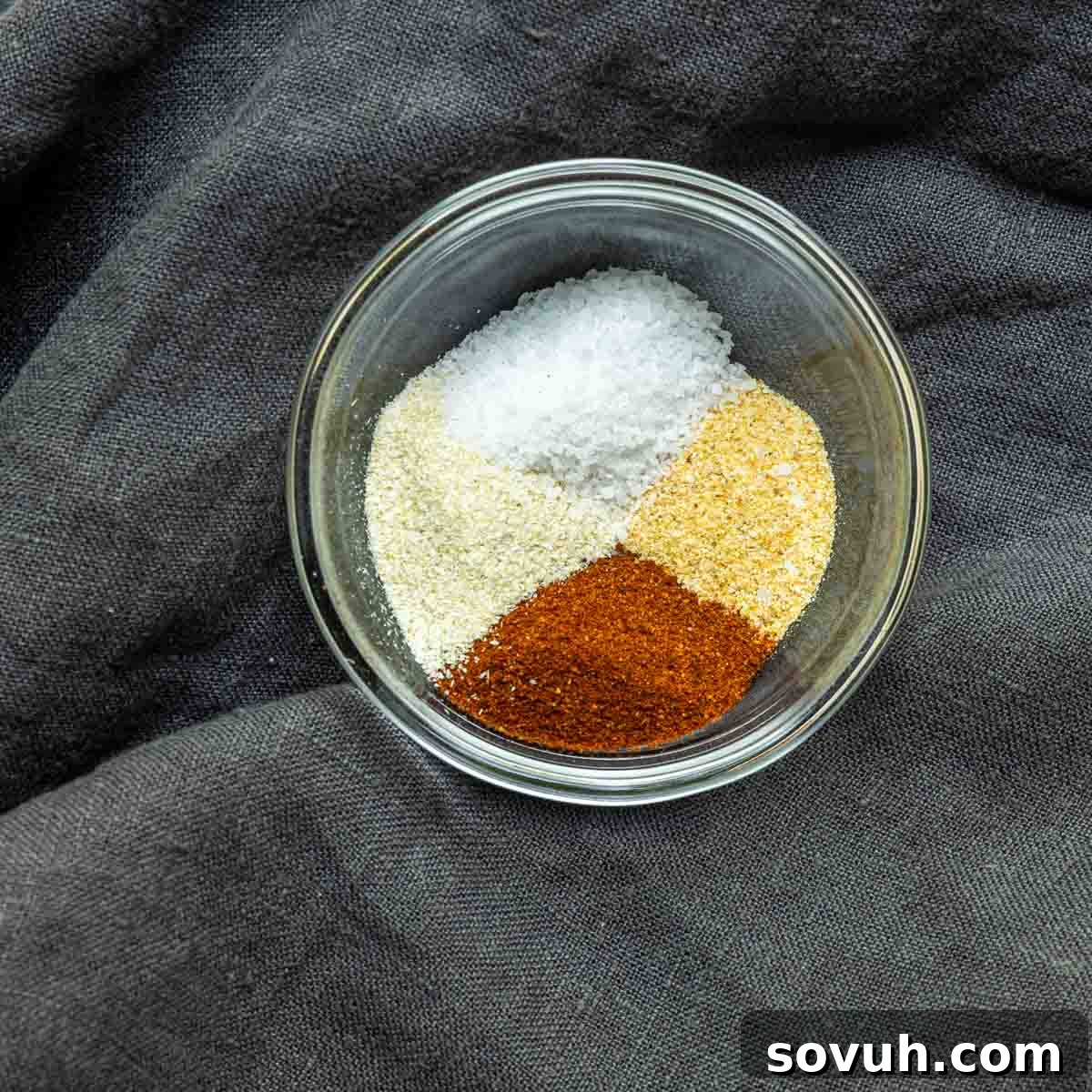 A small bowl holding a dry rub mixture for seasoning chicken wings.