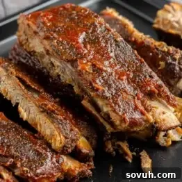 Succulent St Louis-Style Ribs served on a black plate, featuring a rich, crispy coating and tender meat falling off the bone.